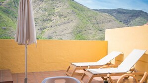 Eine Terrasse mit Esstisch, einer Weinflasche und Blick auf Berge.