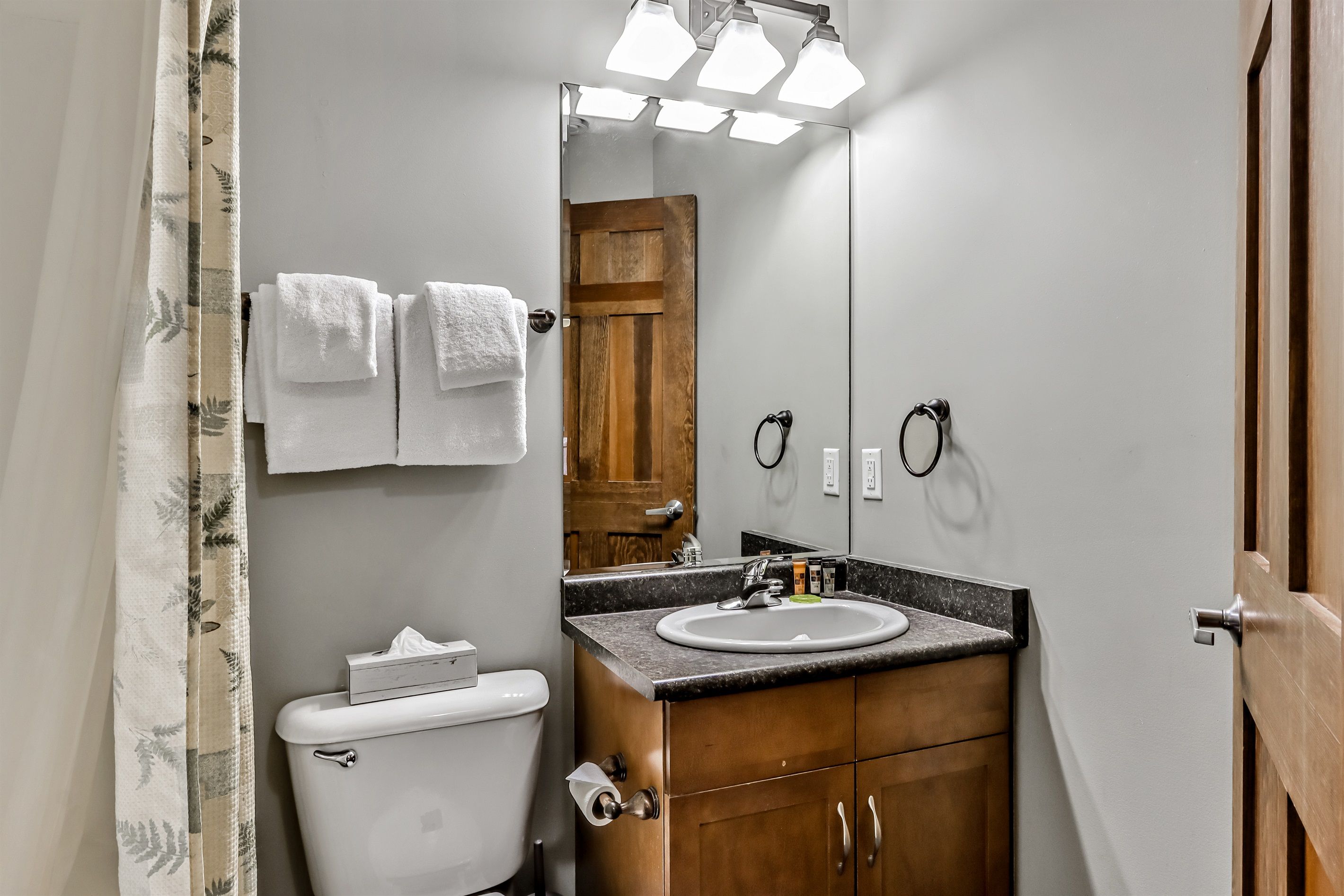 A bathroom with a toilet, sink, and mirror.