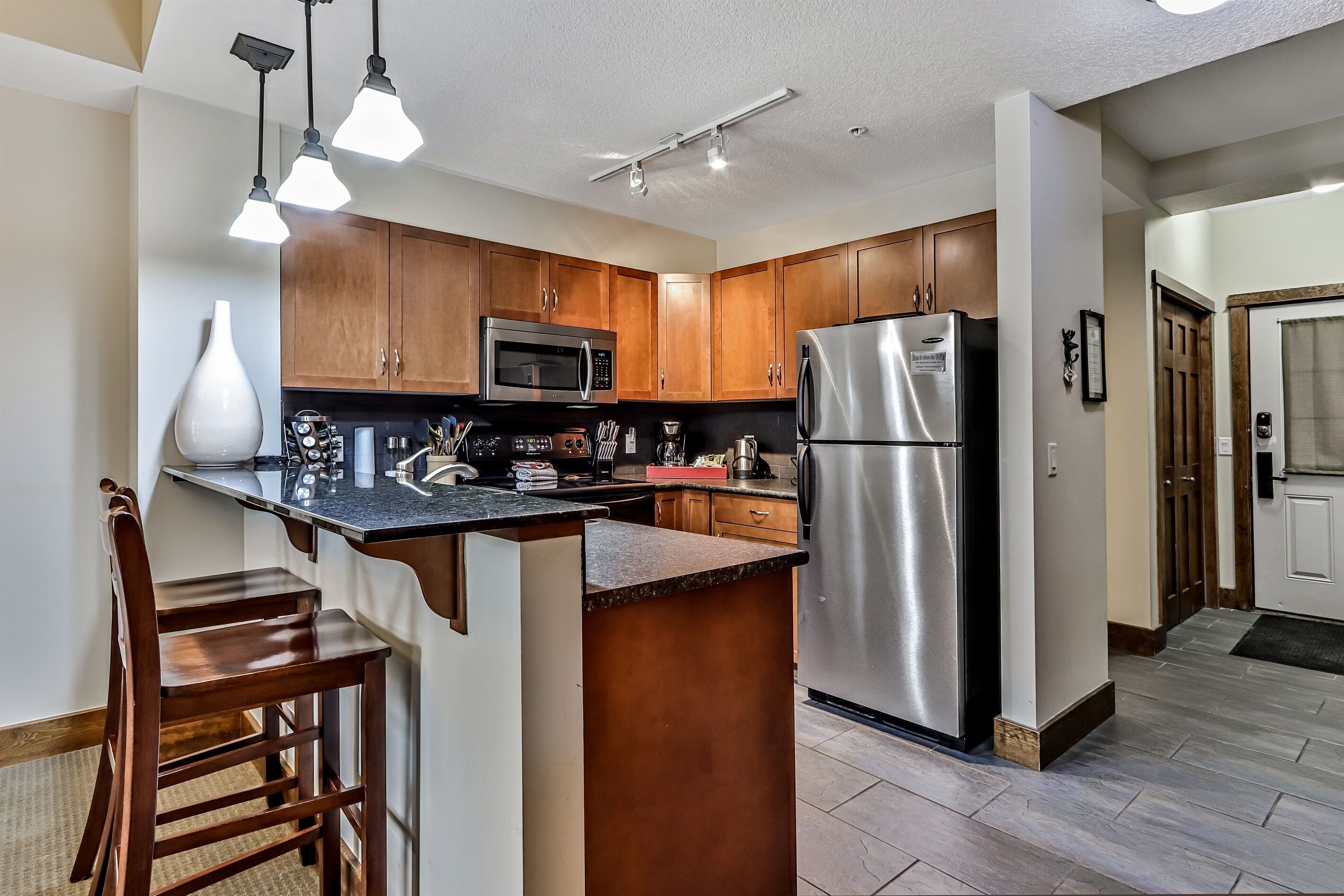 A modern kitchen with wooden cabinets, stainless steel appliances, and a central island.