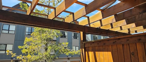 Terraza de madera con vistas a un edificio moderno y un árbol.