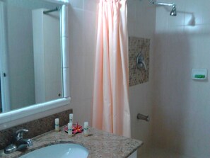 Een bad/douchecombinatie, een bubbelbad, een haardroger, handdoeken