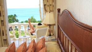 Ein Schlafzimmer mit Meerblick, einem hölzernen Kopfteil und einem Balkon, auf dem sich eine Person entspannt.
