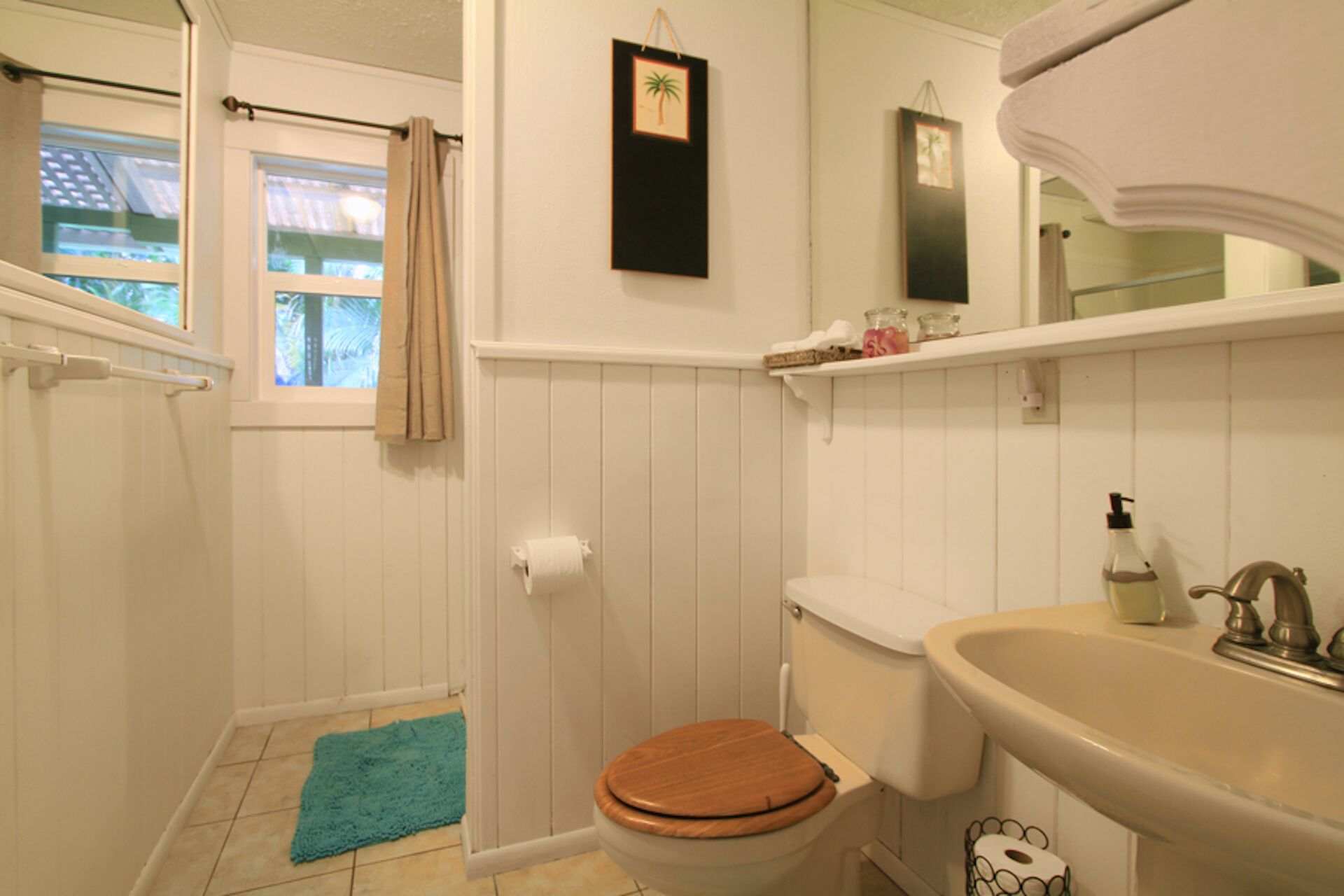A bathroom with a toilet, sink, and window.