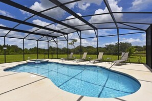 A covered outdoor swimming pool with lounge chairs and a hot tub.