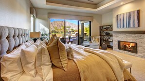 Ein Schlafzimmer mit einem großen Bett, einem Kamin und Bergblick durch eine Glasschiebetür.