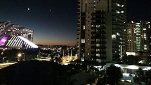 A high-rise building with multiple floors and balconies, surrounded by other tall buildings.