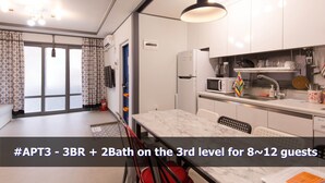 A modern kitchen with white cabinets, a marble countertop, and a hanging pendant light. - Ur Seoul Home (Seoul)