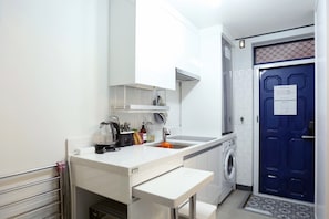 A compact kitchen with a built-in washing machine, a sink, and a countertop with various kitchen items. - Ur Seoul Home (Seoul)
