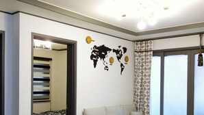 A modern living room with a sofa, a world map wall decoration, and a large window. - Ur Seoul Home (Seoul)