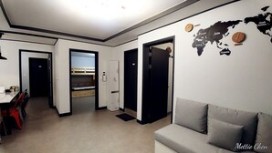 A modern living room with a grey sofa, a world map on the wall, and a bunk bed in the background. - Ur Seoul Home (Seoul)