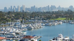 A marina with numerous boats docked, a city skyline in the background, and a clear sky. - Corondo Shores Unique  & Beautiful Condo -  Stunning Views!!!  Pet Welcome! (Coronado)