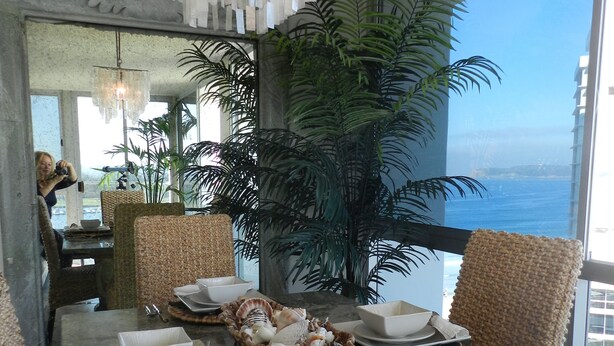 A dining area with a view of the ocean, a chandelier, and potted plants. - Corondo Shores Unique  & Beautiful Condo -  Stunning Views!!!  Pet Welcome! (Coronado)
