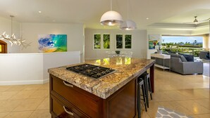 A modern kitchen with a granite countertop, stainless steel appliances, and pendant lighting. - Spectacular 3rd Row Villa at Ho'olei with Ocean Views (Kihei)