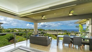 A spacious balcony with a view of the ocean, furnished with wicker chairs and a sofa, and a ceiling fan. - Spectacular 3rd Row Villa at Ho'olei with Ocean Views (Kihei)