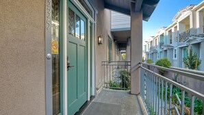 A building with a green door, a no smoking sign, and a balcony with railings.