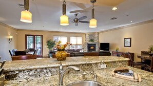 A kitchen with granite countertops, a stainless steel sink, and pendant lighting.