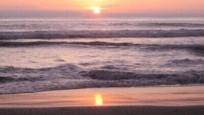 A sunset over the ocean with waves approaching the shore.