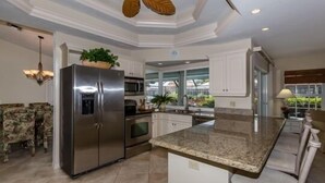 A modern kitchen with a stainless steel refrigerator, granite countertop, and a ceiling fan. - Waterfront home on the famous Paradise Coast (Marco Island)