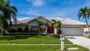 A single-story house with a red door, white siding, and a tiled roof. - Waterfront home on the famous Paradise Coast (Marco Island)