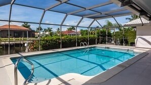 A covered swimming pool with a clear view of the surrounding area, including a house and greenery. - Waterfront home on the famous Paradise Coast (Marco Island)