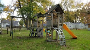 A playground with a wooden climbing structure and a slide. - Gun Lake Cottage shared lake frontage, 7 Miles to Casino, Volleyball Playgrounds (Wayland)