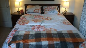 Een slaapkamer met een bed, twee nachtkastjes en een schilderij aan de muur.