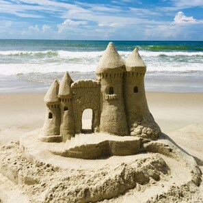 Un castello di sabbia con diverse torri e un arco centrale su una spiaggia.