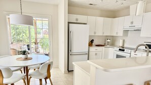 Una cocina moderna con armarios blancos, una isla central y una zona de comedor con una mesa redonda y sillas.