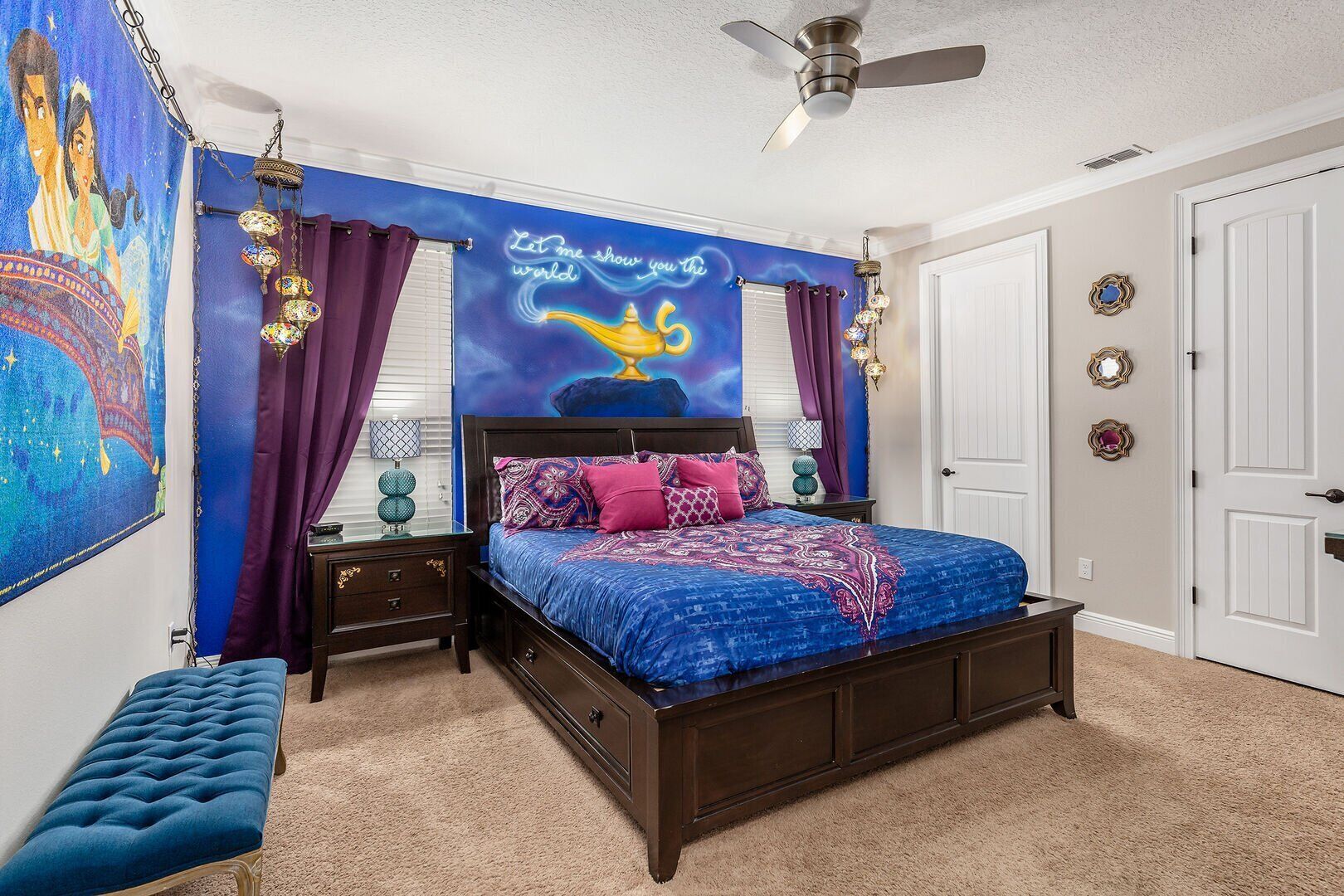 A bedroom with a bed, nightstands, a bench, and a ceiling fan.