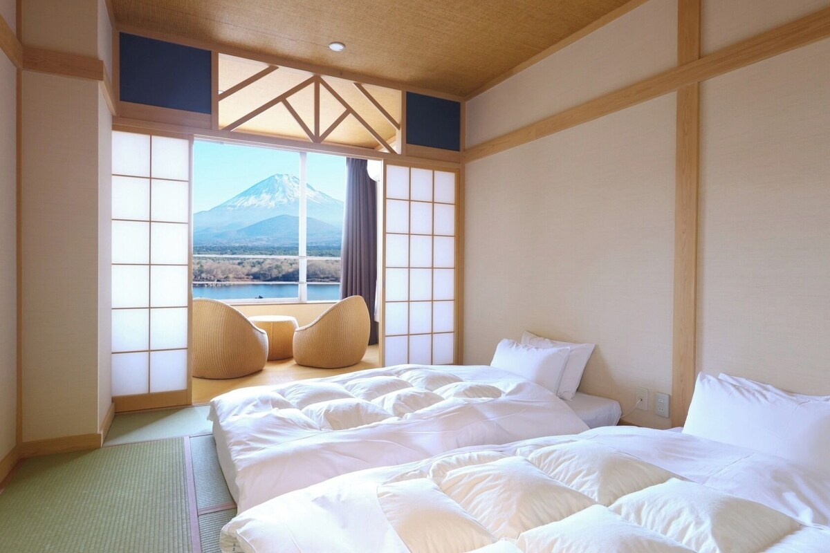 Quarto com cama, vista para uma montanha e portas corrediças tradicionais japonesas.