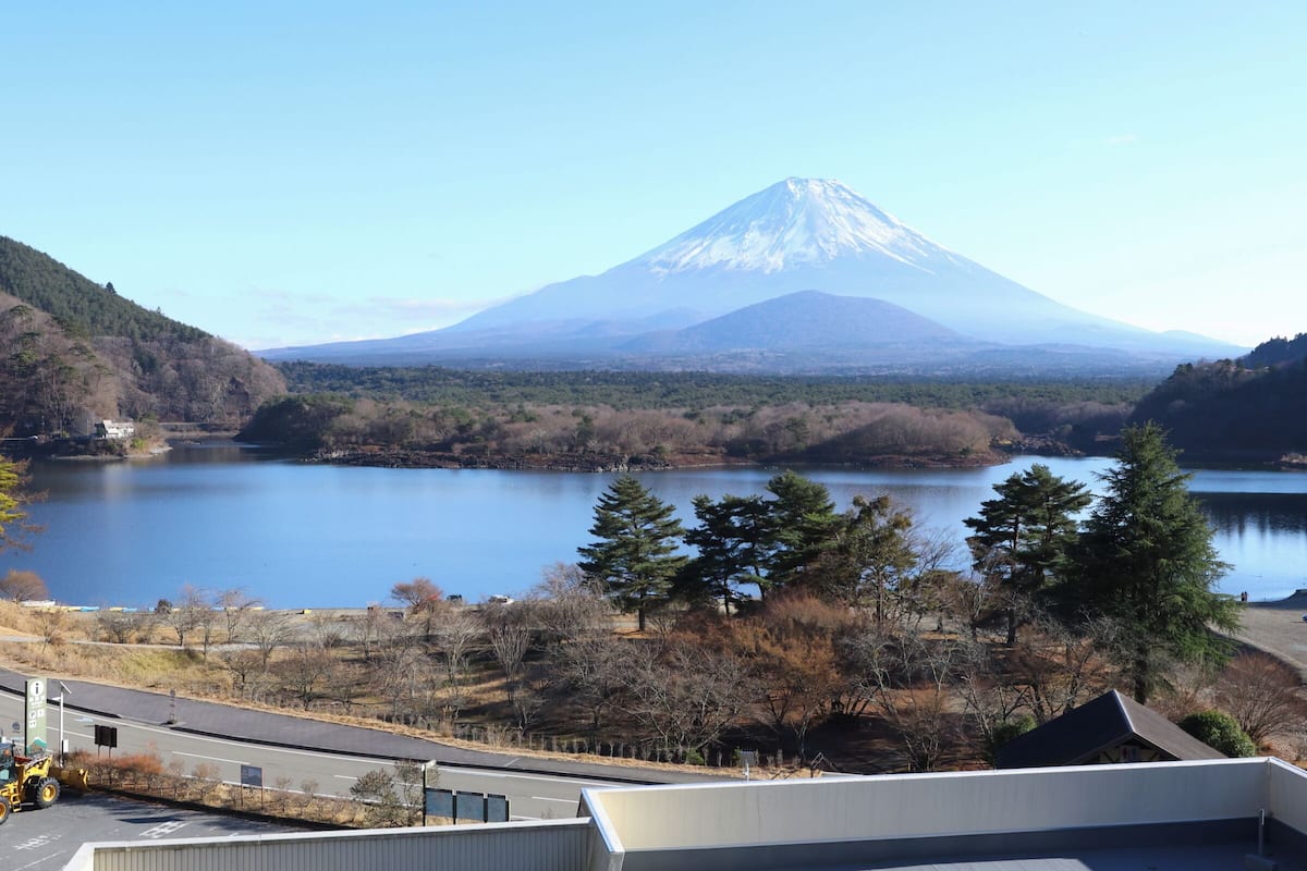 Vista del monte Fuji, un lago y colinas cubiertas de bosque.