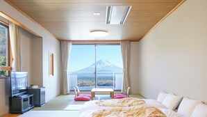 Een hotelkamer met een bed, een televisie, een tafel en uitzicht op een berg.