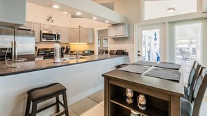 Une cuisine moderne dotée d’un îlot central, d’appareils électroménagers en acier inoxydable et d’un coin repas avec une table et des chaises.