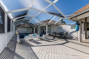 Un espacio al aire libre techado con piscina, sillas de descanso y una mesa.