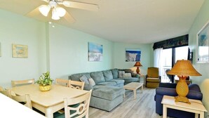 A living room with a sofa, a dining table, chairs, a lamp, and artwork on the walls. - Sea View at Sand Dunes Resort (Myrtle Beach)