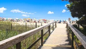 A wooden boardwalk leading to a beach with umbrellas and people. - Sea View at Sand Dunes Resort (Myrtle Beach)