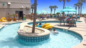 A pool area with a hot tub, lounge chairs, and umbrellas. - Sea View at Sand Dunes Resort (Myrtle Beach)
