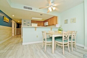 Une cuisine moderne avec des meubles en bois, un îlot central doté de chaises et un ventilateur de plafond.