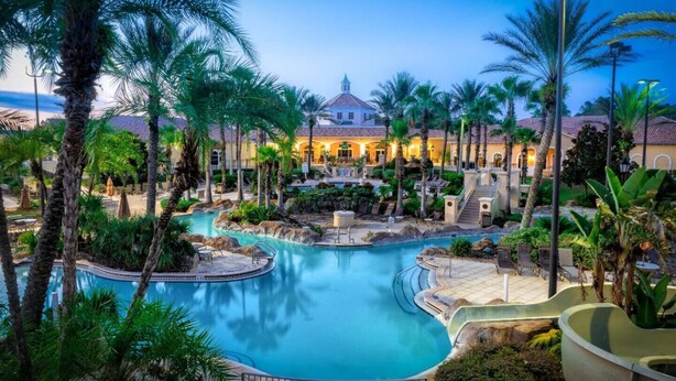 Un resort con una piscina grande, palmeras y un edificio con techo abovedado.