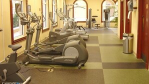 Un gimnasio con cintas de correr, bicicletas estáticas y una banca para pesas.