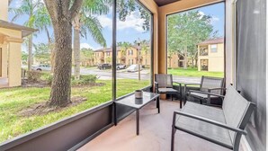 Un balcón con vistas a una zona residencial, que incluye un árbol y coches aparcados.