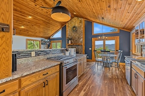 A spacious kitchen with a stone accent wall, wooden cabinets, and a large island with seating.