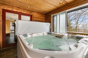 Un jacuzzi en una cabaña de madera con vistas a árboles.