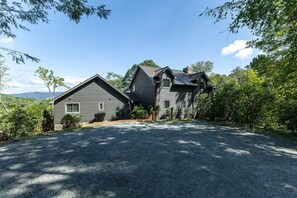 A two-story house with a gravel driveway and a view of the surrounding landscape.