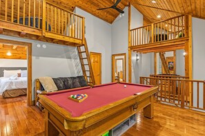 A room with a pool table, a bunk bed, and a loft area.