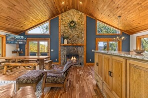 A spacious room with a stone fireplace, wooden ceiling, and a large dining table.