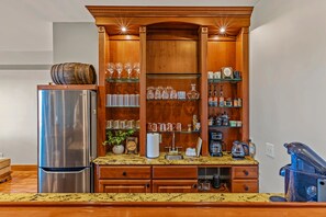 A kitchen with a built-in wooden cabinet, stainless steel refrigerator, and a coffee machine. - 10 Min to Banner Elk | Sleeps 19 | Hot Tub, Sauna, Movie Theater & Mountain Views (Banner Elk)