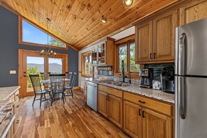 A modern kitchen with wooden cabinets, stainless steel appliances, and a dining area with a table and chairs.