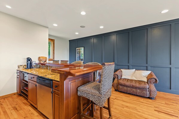 A kitchen with a bar area, wooden cabinets, and a dark paneled wall.