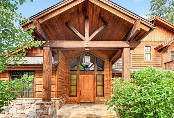 A wooden cabin with a stone foundation, a large wooden door, and a covered porch.